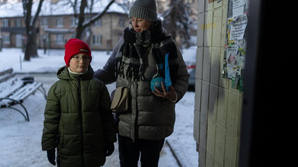 Une femme et un enfant dans une zone urbaine enneigée en Ukraine.